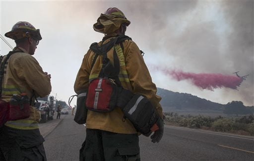 Two fire captains with the Loma Linda Fire Department watch as a tanker flies in low to drop fire retardant on a wildfire burning close to Highway 94 near Potrero, Calif., on Monday, June 20, 2016. (Hayne Palmour IV/San Diego Union-Tribune via AP)