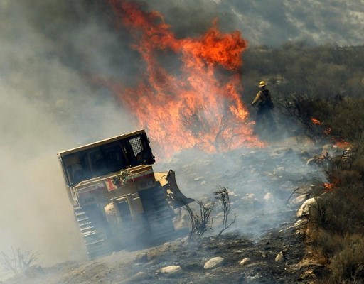 Firefighters create a firebreak as they work to stop the advance a wildfire near the town of Acton, Calif., Monday, July 25, 2016. A firefighting army converged Monday on a dangerous wildfire burning in the mountainous northern fringe of metropolitan Los Angeles after it wildly expanded and forced thousands of people from their homes during the weekend. (AP Photo/Nick Ut)