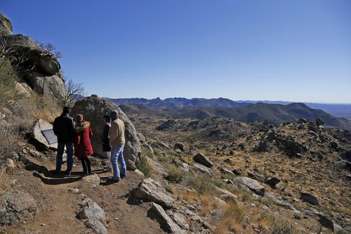 Hikers read a plaque along a trail after a dedication ceremony for the new Granite Mountain Hotshots Memorial State Park as a tribute to the 19 firefighters killed during a 2013 wildfire Tuesday, Nov. 29, 2016, in Yarnell, Ariz. Gov. Doug Ducey said the 3-mile trail and memorial would serve as a lasting tribute to the fallen firefighters' heroism. (AP Photo/Ross D. Franklin)