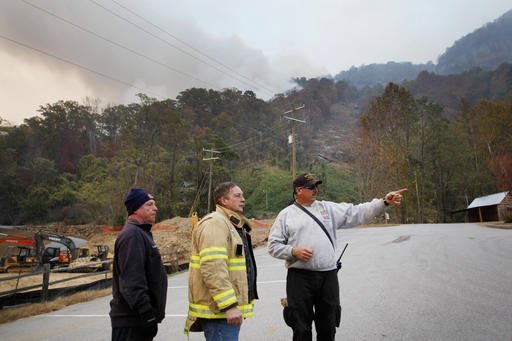 In a Saturday, Nov. 12, 2016 photo, from left, Stacey Graves, of Chapel Hill Fire Department, Steve West, of East Howellsville Fire Department, and Mack Cabe, of Orange Rural Fire Department, strategize how to protect a home near the fire in Chimney Rock, NC. North Carolina Gov. Pat McCrory on Monday planned update residents on wildfires in western North Carolina as officials report some progress in containing the blazes. (Angela Wilhelm/The Asheville Citizen-Times via AP)