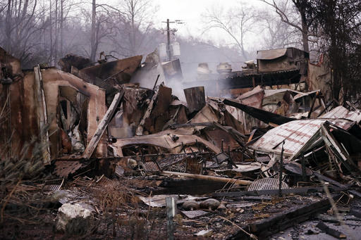 FILE -In this Wednesday, Nov. 30, 2016 file photo, smokes rises out of the remains of a burned-out business, in Gatlinburg, Tenn., after a wildfire swept through the area Monday. Wildfires ravaged the tourist town of Gatlinburg, in the shadow of the Great Smoky Mountains, killing 14 people, destroying businesses and leaving hundreds of people homeless just after Thanksgiving. The devastation was voted Tennessee’s top for 2016 in a poll of Associated Press editors and broadcasters, followed by the Nov. 21 school bus crash in Chattanooga that left six elementary school children dead. (AP Photo/Mark Humphrey, File)